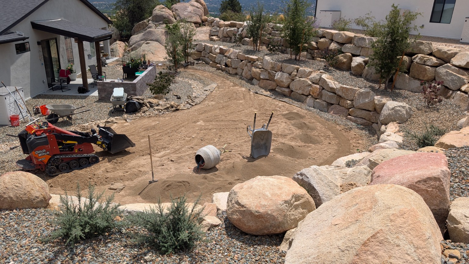 Large artificial turf lawn with natural boulders and retaining walls